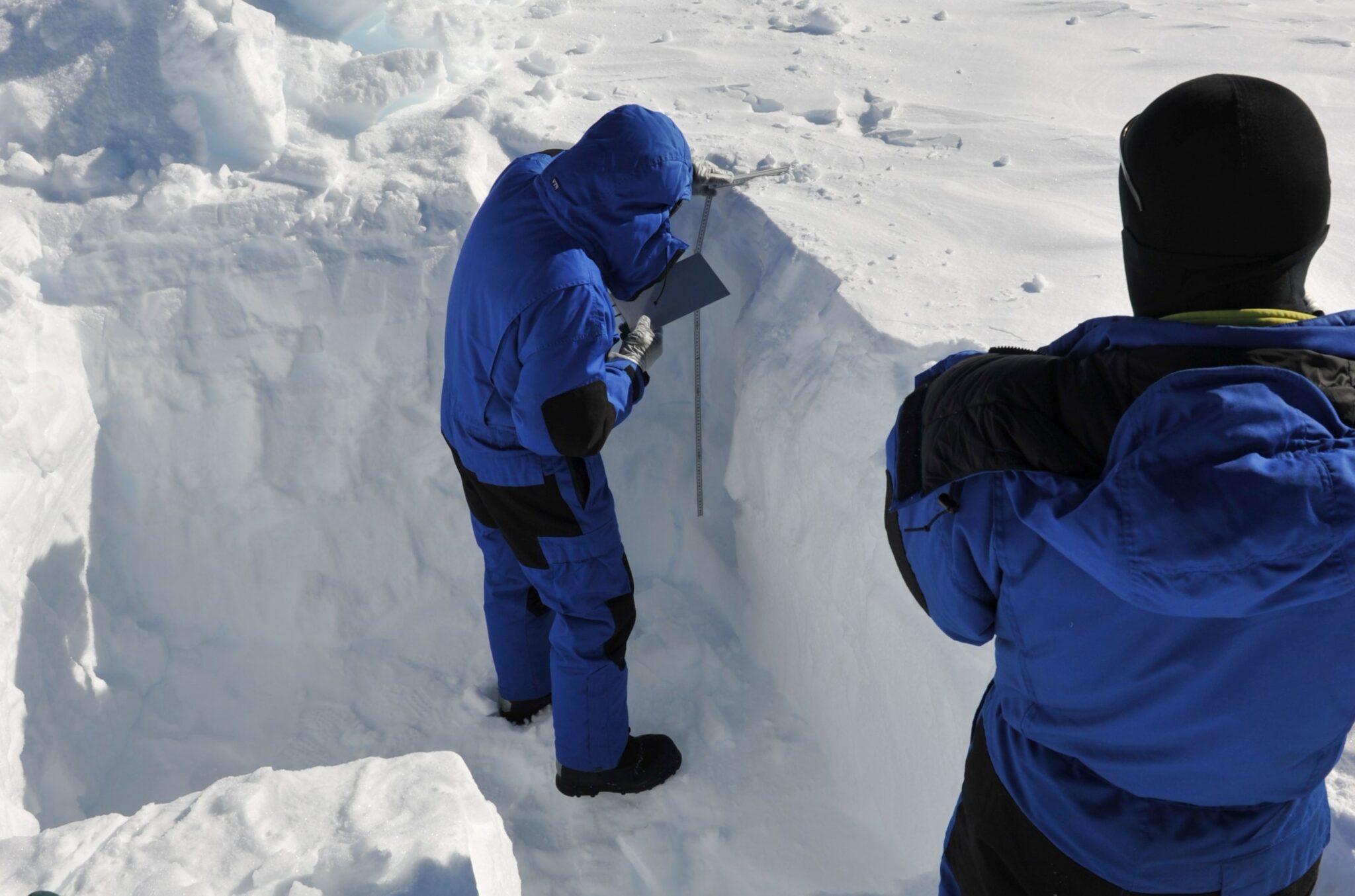 L'équipe a creusé un trou dans la neige pour pouvoir récupérer des échantillons de neige. Ils s'assurent que l'endroit choisi n'a jamais été piétiné par quiconque.